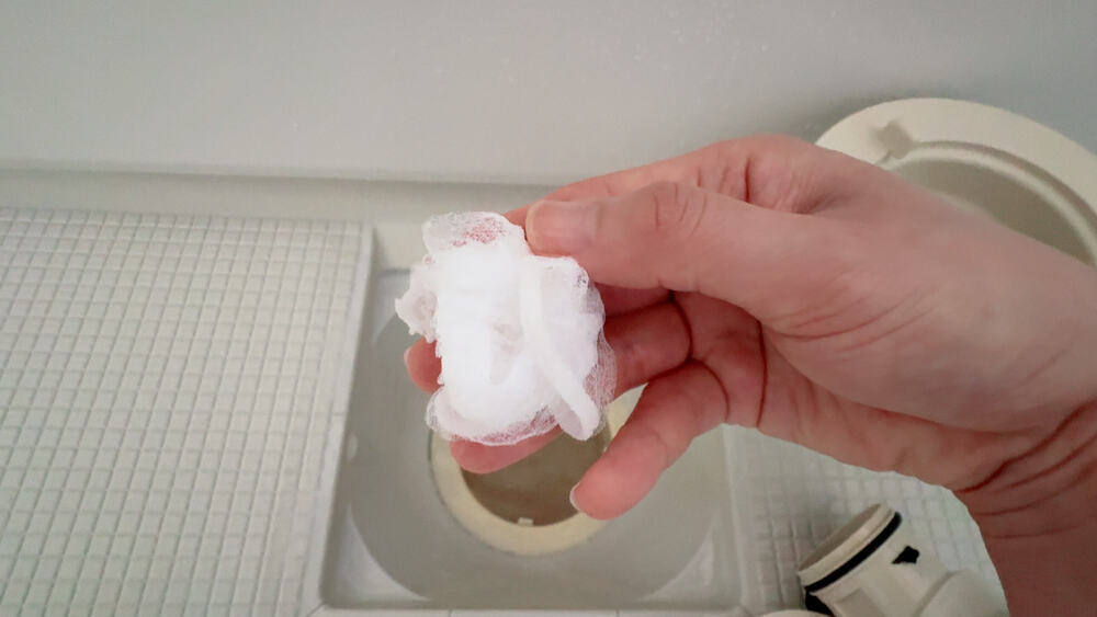お風呂の排水溝を水切りネットで掃除している。