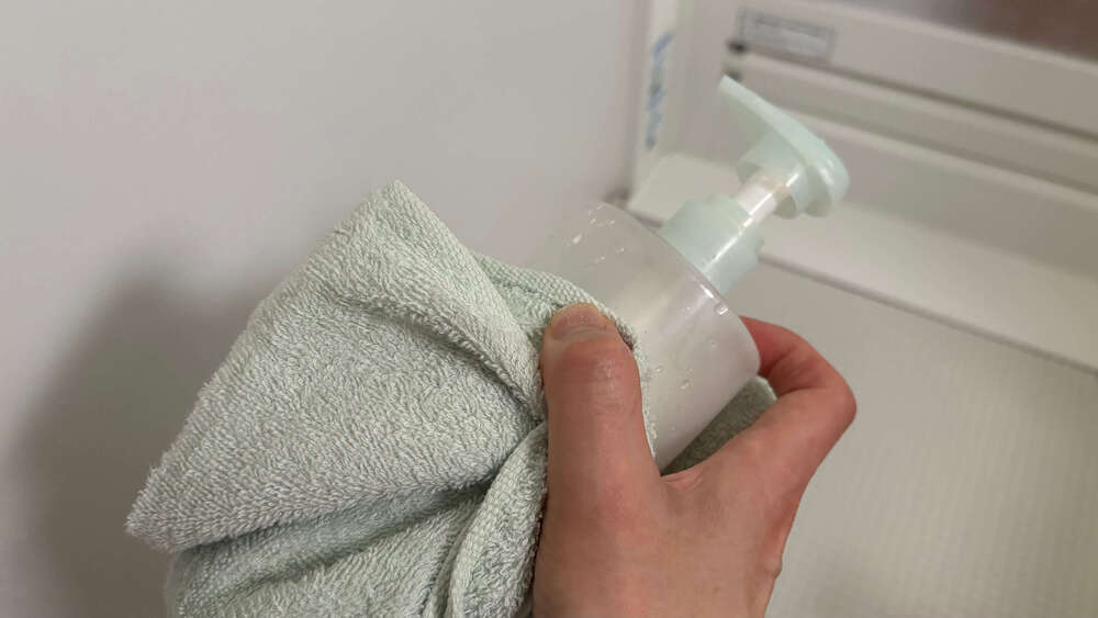 ボディーソープの容器の水をタオルで拭いている。